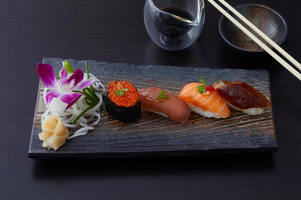 a plate with sushi and vegetables on a table at Strandhotel Fontana in Timmendorfer Strand