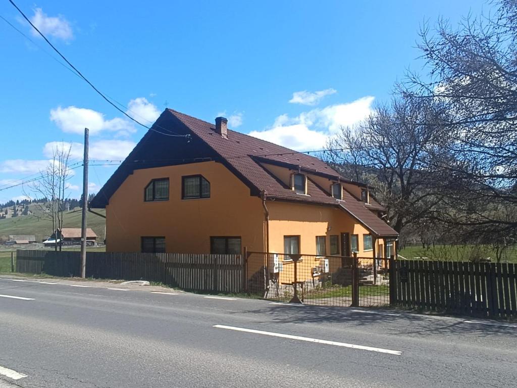 a yellow house with a black roof on the side of the road at Karacsony Guest House in Lunca de Sus