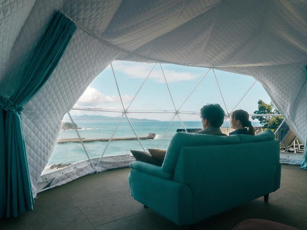 two people sitting in a couch looking out at the ocean at Yamamizuki in Shimanto