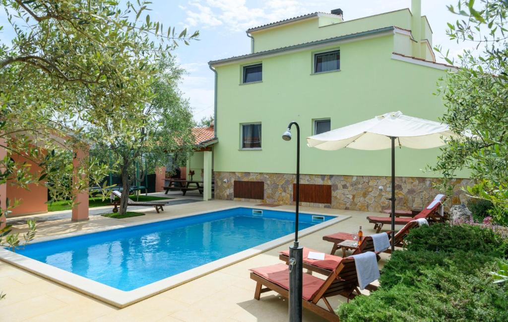 a pool in front of a house with chairs and an umbrella at Stunning Home In Peruski in Peruški