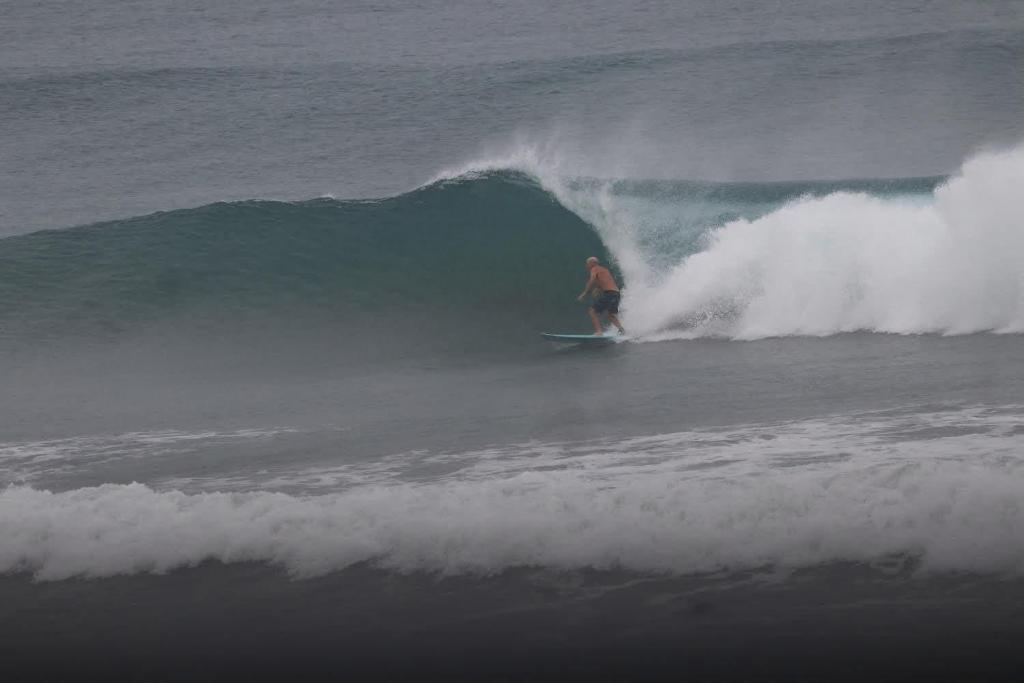 a man riding a wave on a surfboard in the ocean at Surf Front Villa Samar in Maydolong