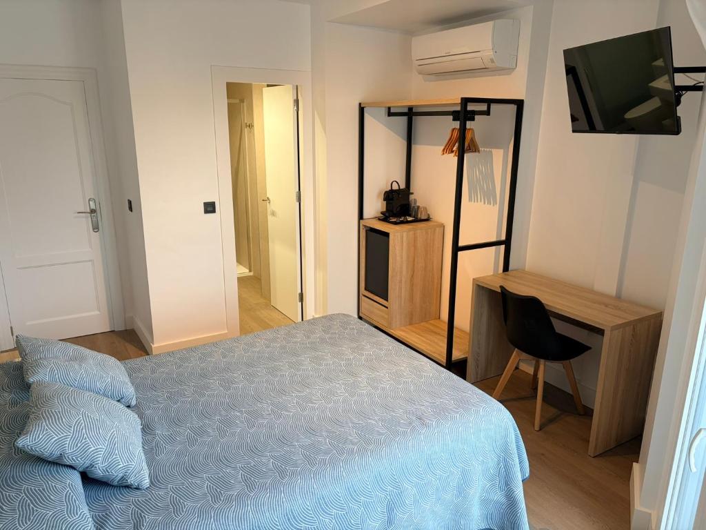 a bedroom with a bed and a desk and a television at Hostal Juan Carlos in Carboneras