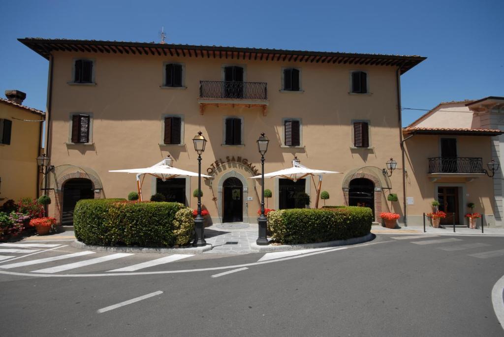 a large building with umbrellas in front of a street at Sangallo Hotel in Monte San Savino