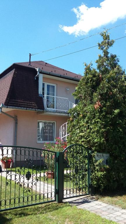 a fence in front of a house with a tree at Fődi apartman in Zalakaros