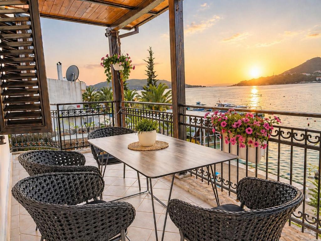 a table and chairs on a balcony with a view of the water at Old Sailor`s house Rafailovici in Rafailovici