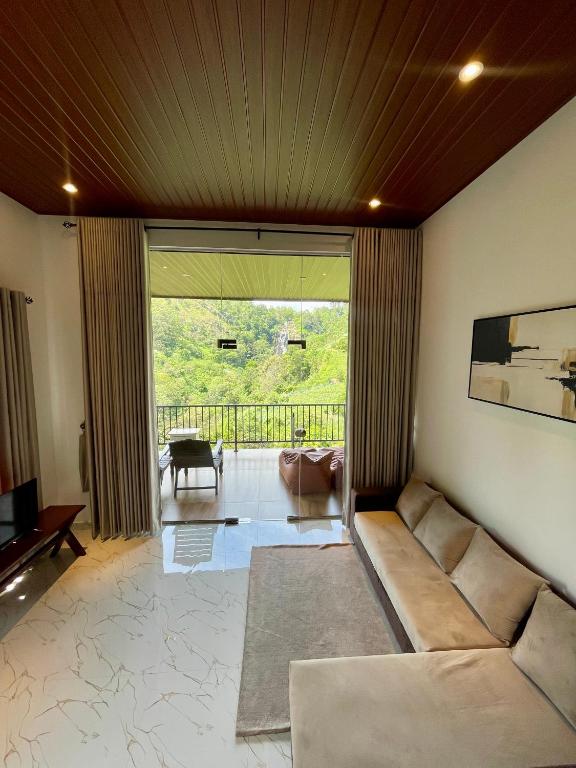 a living room with a couch and a large window at Ella waterfall view in Ella