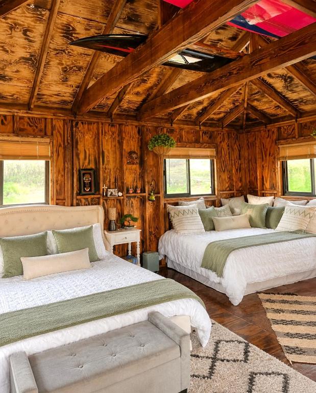 two beds in a room with wooden walls at Pipeline Tropical Bungalow in Haleiwa