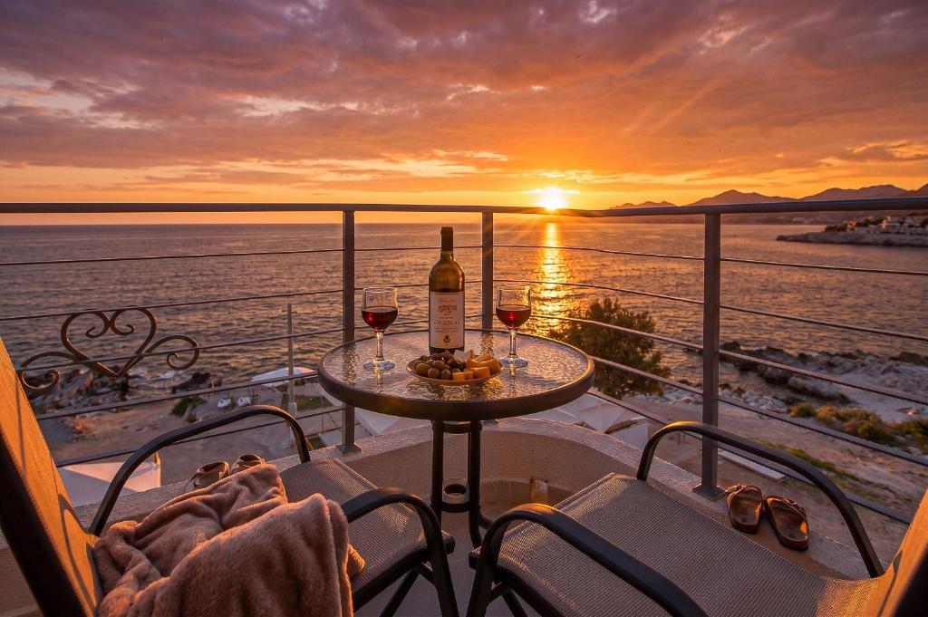 a table with two glasses of wine on a balcony with the sunset at Open Sea Apartments in Utjeha