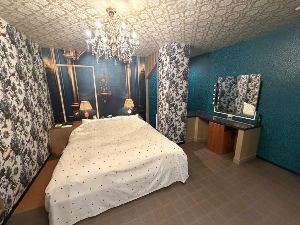 a bedroom with a bed and a blue wall at ホテル 天使と悪魔 in Gobō