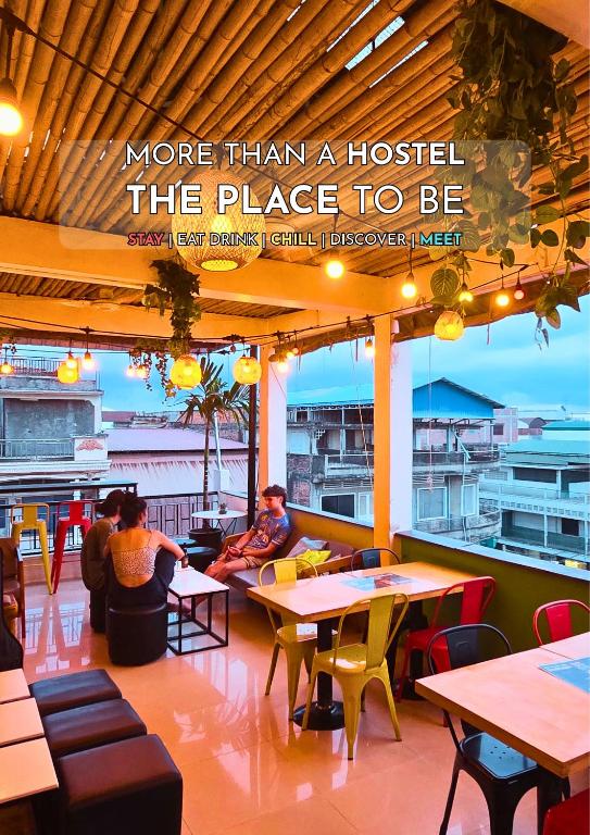 a restaurant with people sitting at tables in a restaurant at THE PLACE Hostel Battambang in Battambang