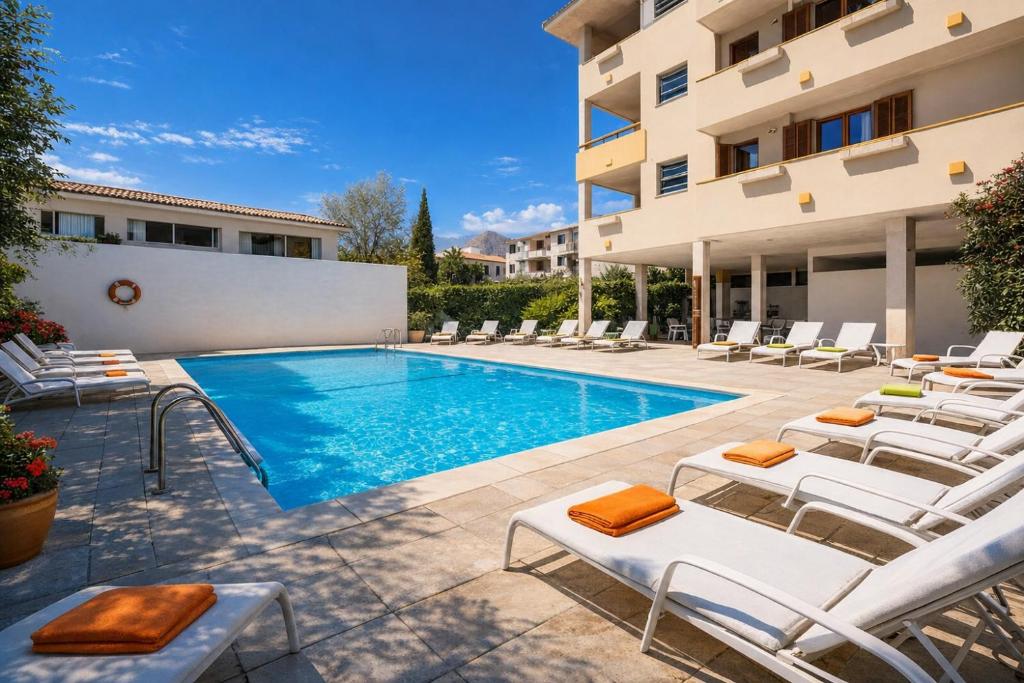 a swimming pool with lounge chairs next to a building at Apartamentos - Penthouse Bressol in Port de Pollensa