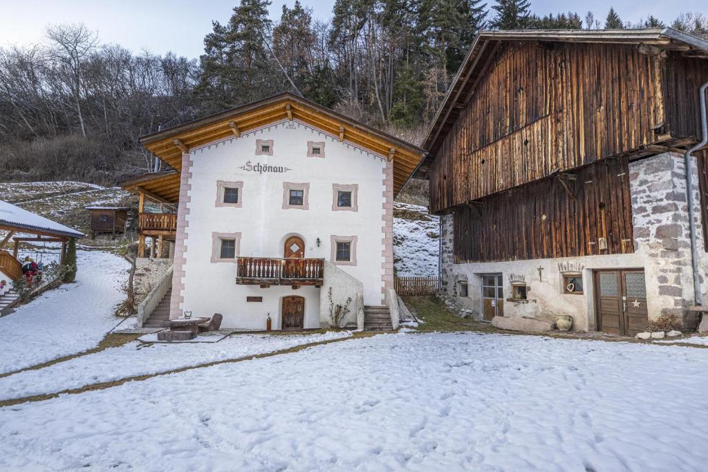 a large white house with a barn in the snow at Schoenau Bio & SPA Family Apartments in San Pietro in Laion
