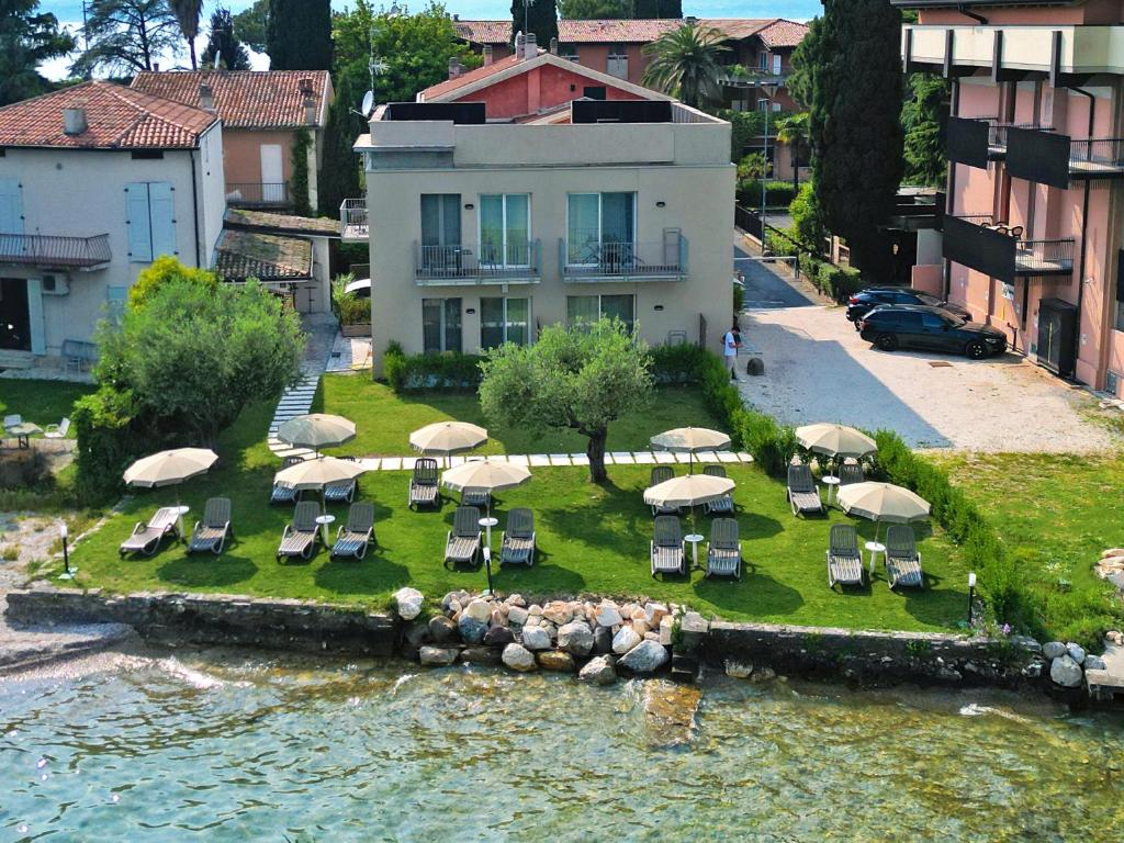 a group of chairs and umbrellas on an island in the water at Smeraldo dip Villa Canneto in Sirmione