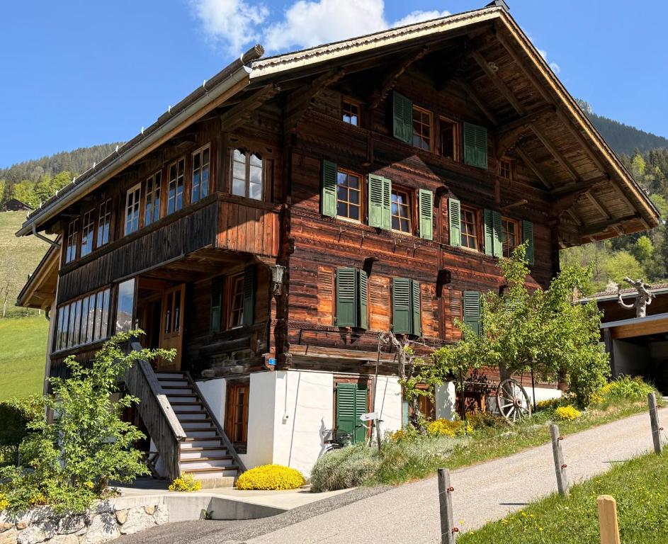 a large wooden house with green shuttered windows and stairs at Blüemlisalp-Huus im Kiental in Kiental