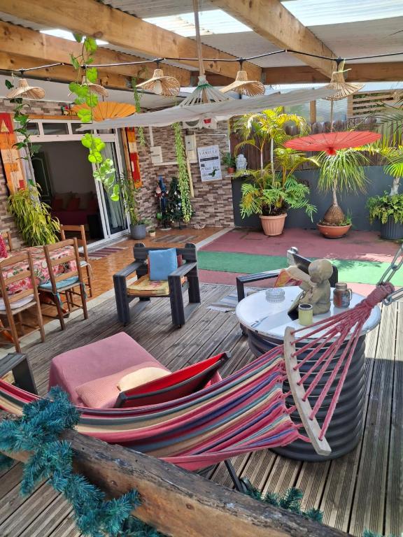 a hammock on a deck with a table and chairs at Le Passager Cilaos maison privée in Cilaos