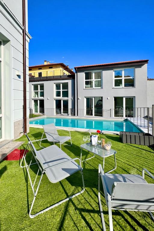a yard with chairs and a table and a swimming pool at Apt Pisces - Oasi di Menaggio in Menaggio