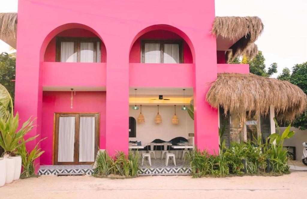 a pink building with a restaurant in front of it at BIG WAVES BOUTIQUE HOTEL SIARGAO in General Luna