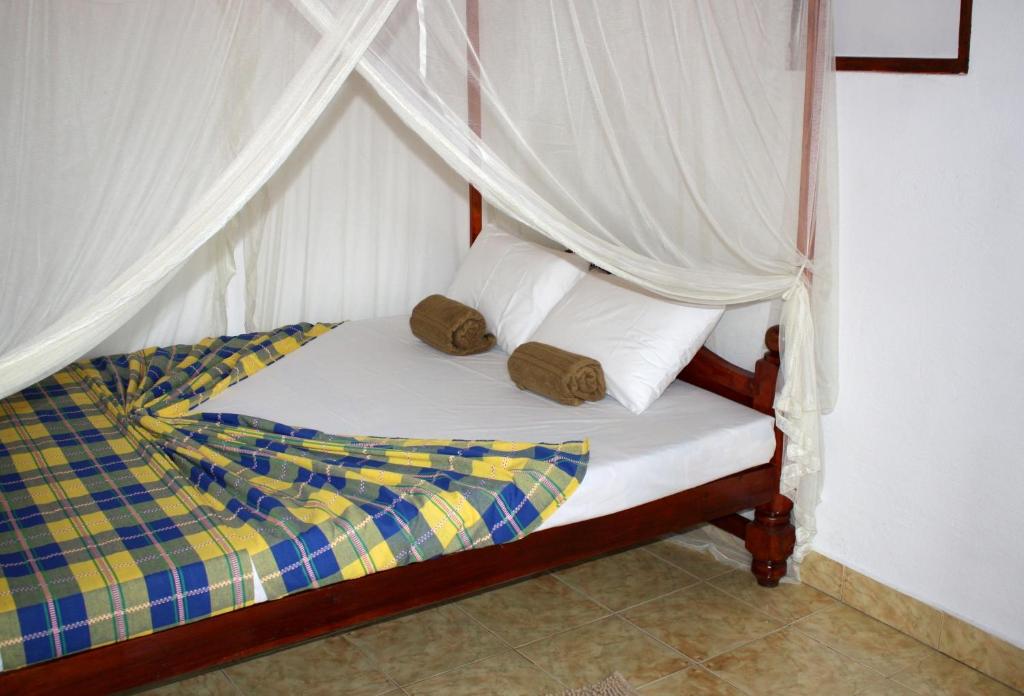 a bedroom with a canopy bed with white sheets and pillows at Happy Coconut in Unawatuna