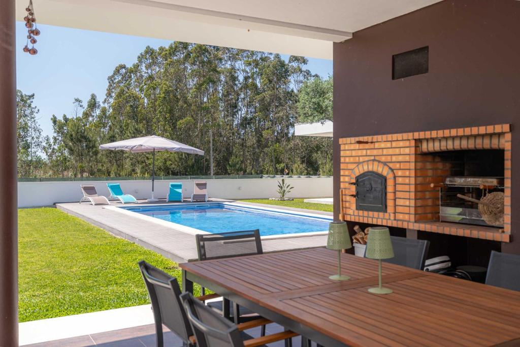 a dining table with a fireplace next to a swimming pool at Marianas in Bom Sucesso