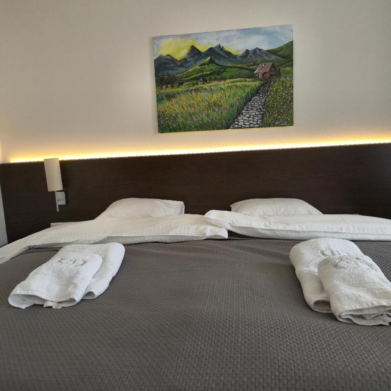 two beds with white pillows and a painting on the wall at Apartmán u Jeleňa in Kežmarok
