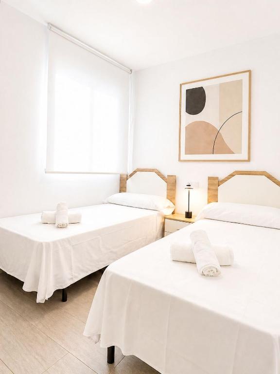 two beds in a room with white walls at Hospedium GL Linarejos Suites Parking Gratis in Linares