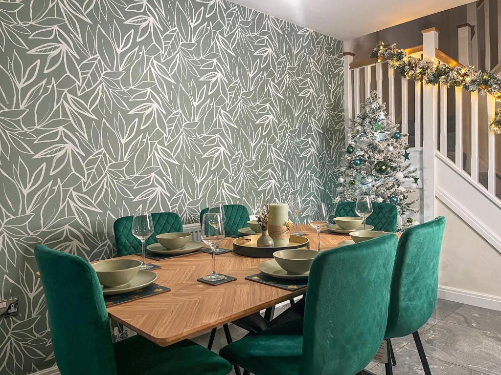 a dining room table with green chairs and a christmas tree at Spring Gardens in Lower Darwen