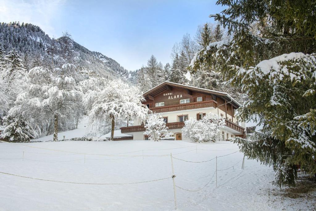 a house in the snow in front at Alara Rooms in Ortisei