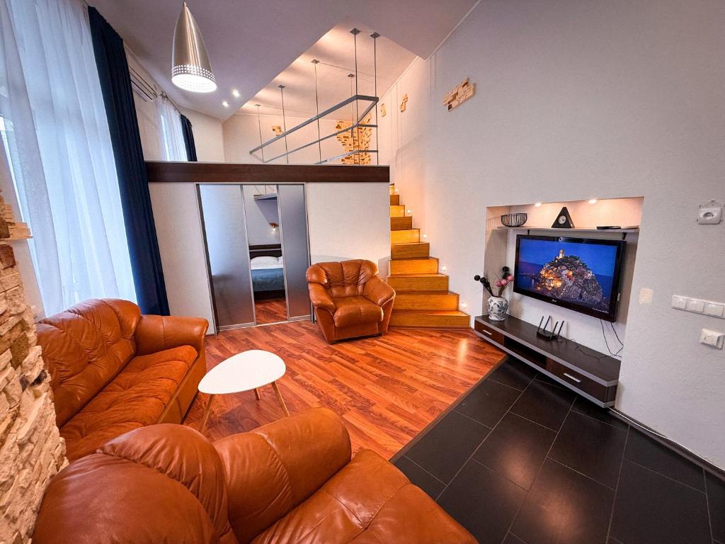 a living room with brown leather furniture and a tv at Kyiv Muse Apartment in Kyiv