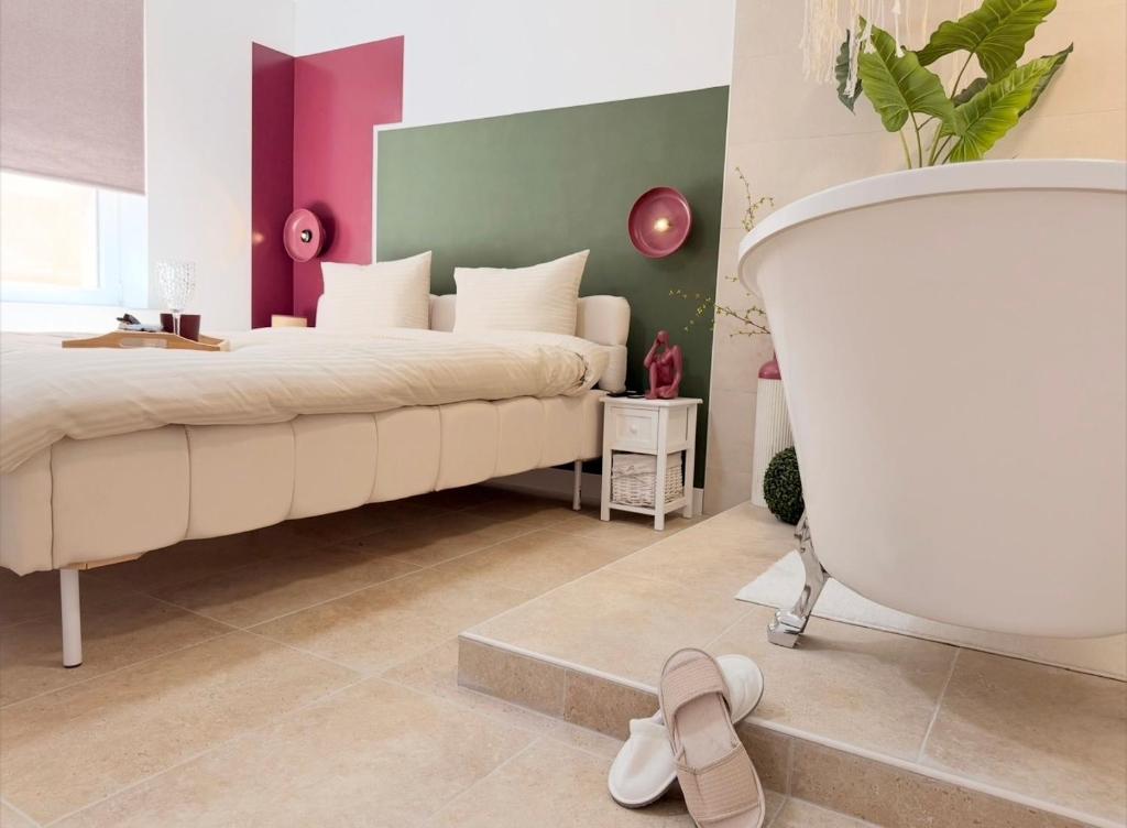 a bedroom with a large bed and a white tub at La Suite Bohème Émeraude in Évreux