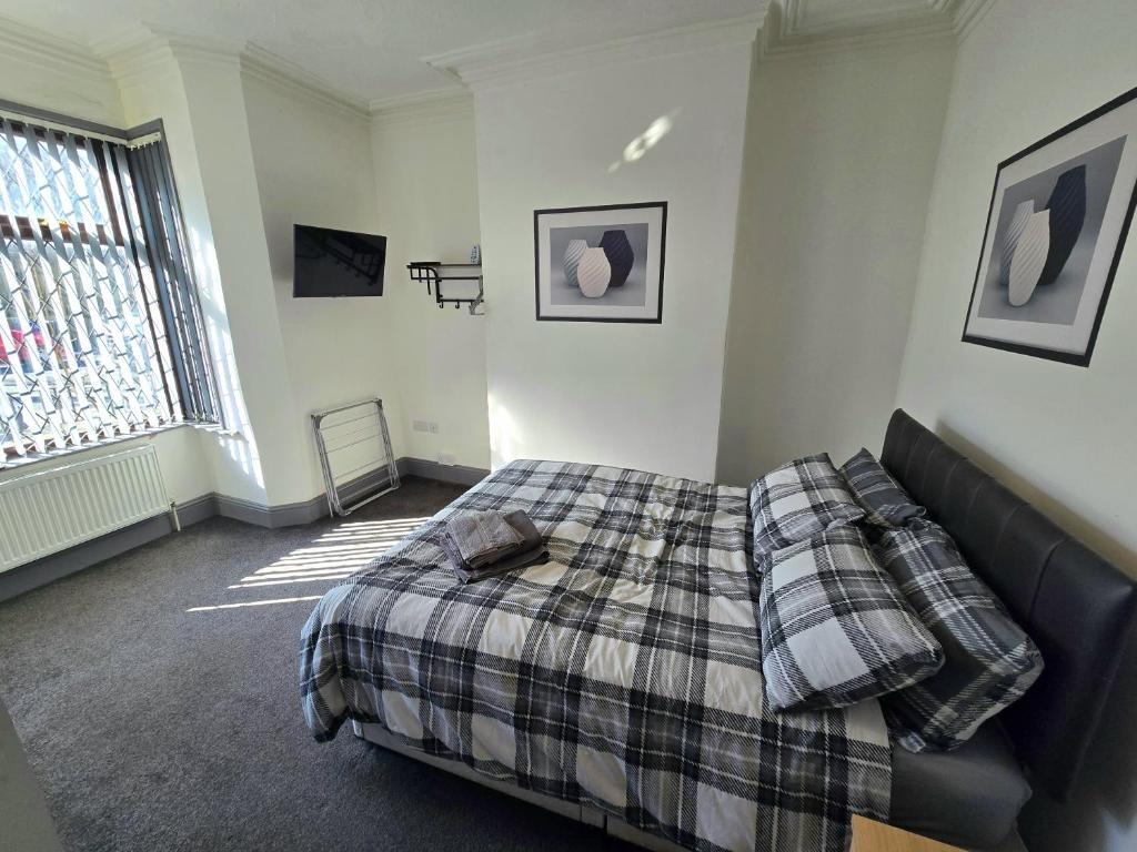 a bedroom with a bed with a plaid blanket at Church Views in Burnley