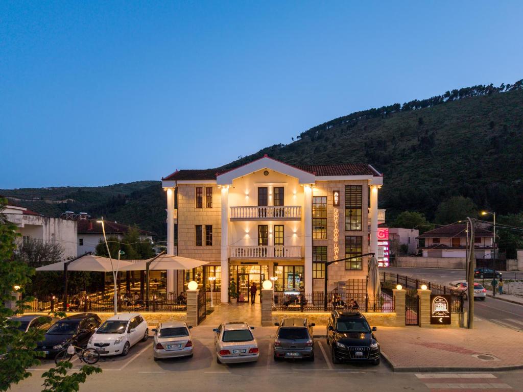 a building with cars parked in a parking lot at Art Boutique Hotel Berat in Berat