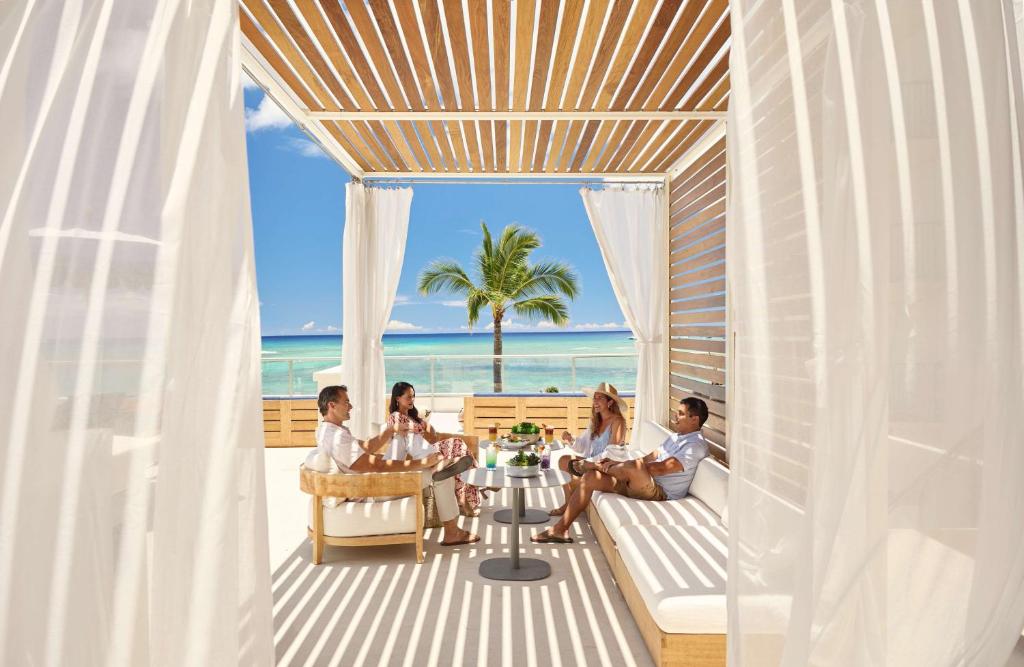 a group of people sitting around a table on the beach at OUTRIGGER Reef Waikiki Beach Resort in Honolulu