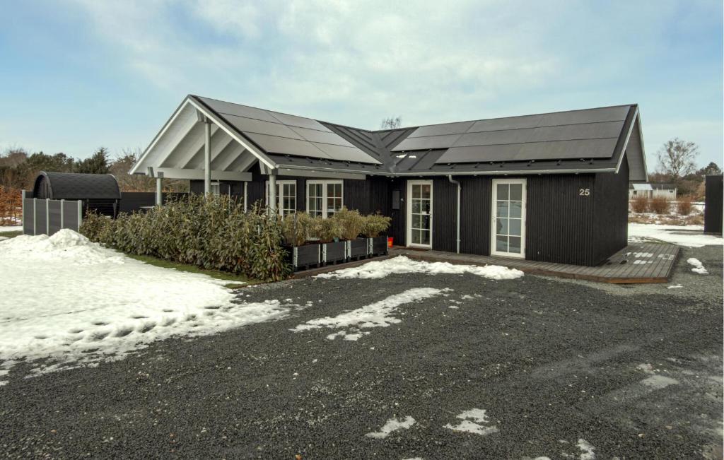 a black house with snow in front of it at Nice Home In Grenaa With Sauna in Grenå