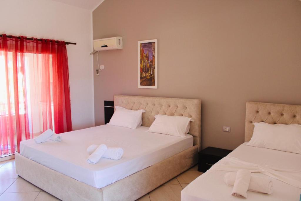 two beds in a room with red curtains at ANORA Mare Suites in Orikum