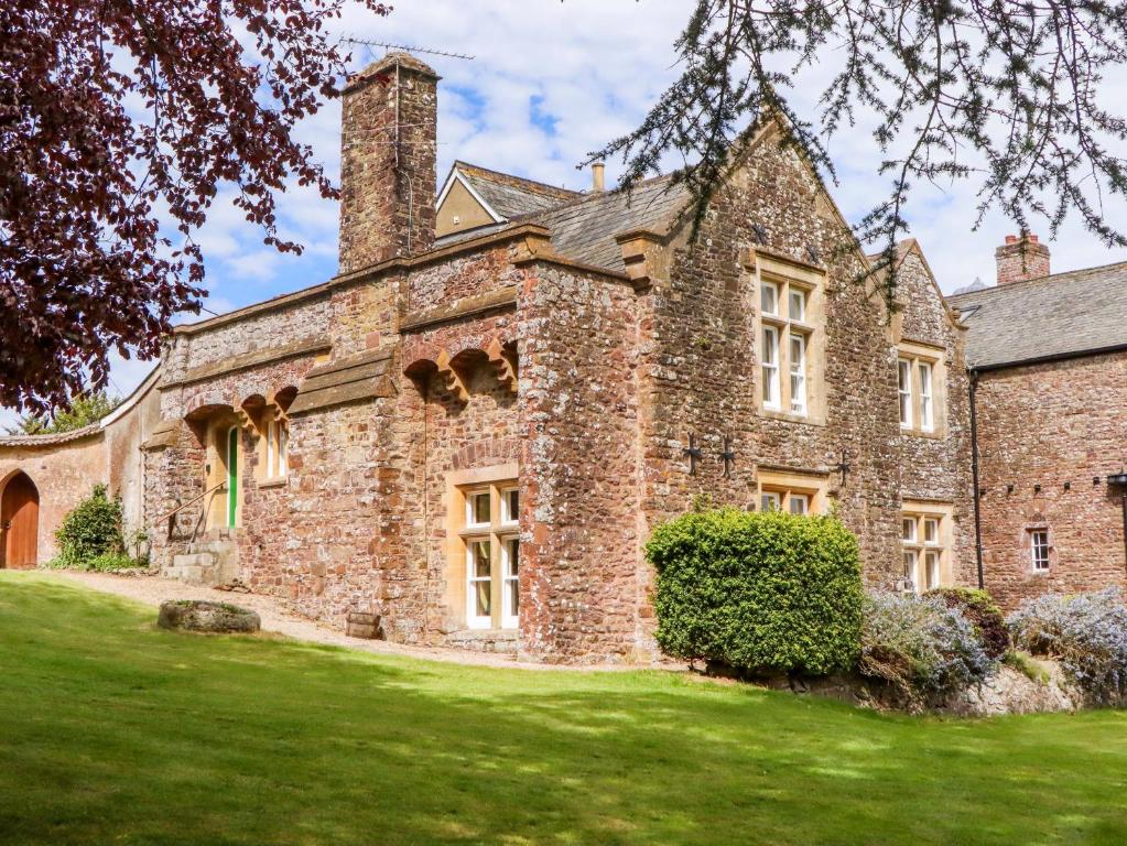 an old stone house with a green yard at Dowrich West Wing Apartment in Crediton
