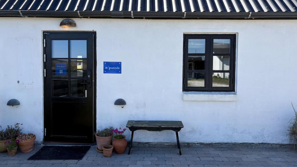 ein weißes Gebäude mit einer Bank vor einer Tür in der Unterkunft Æ Quinta in Klitmøller