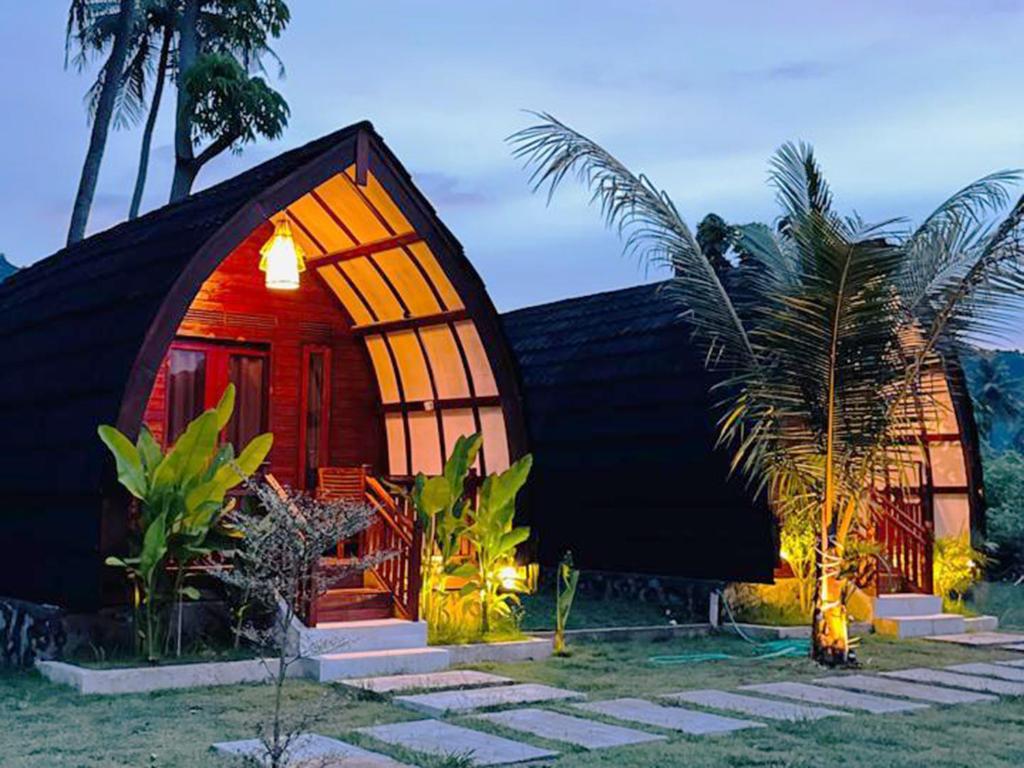 a small house with a black roof and a palm tree at Heyho Bungalow in Maluk