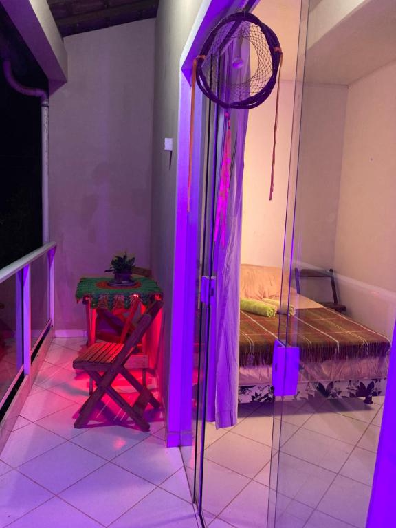 a room with a bed and a table and purple lights at Covil das Trilhas Coliving SÓ PARA MULHERES in Lençóis