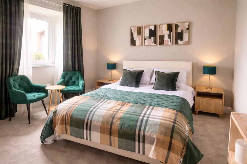 a bedroom with a bed and two green chairs at Station Hotel in Burghead