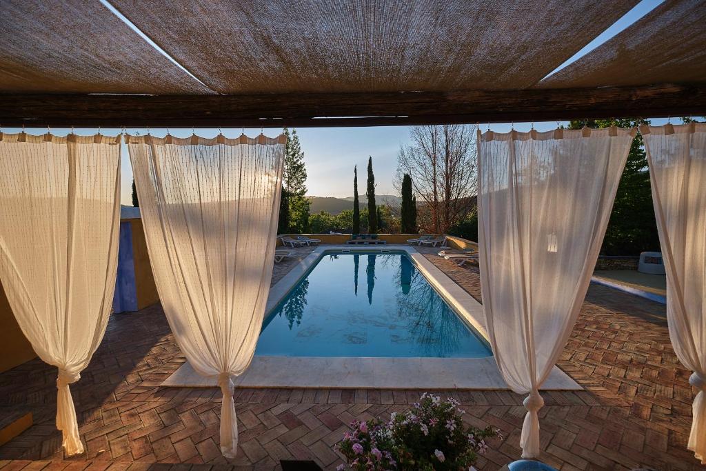 a pool with white curtains at Barrieiro - Art & Nature in Marvão