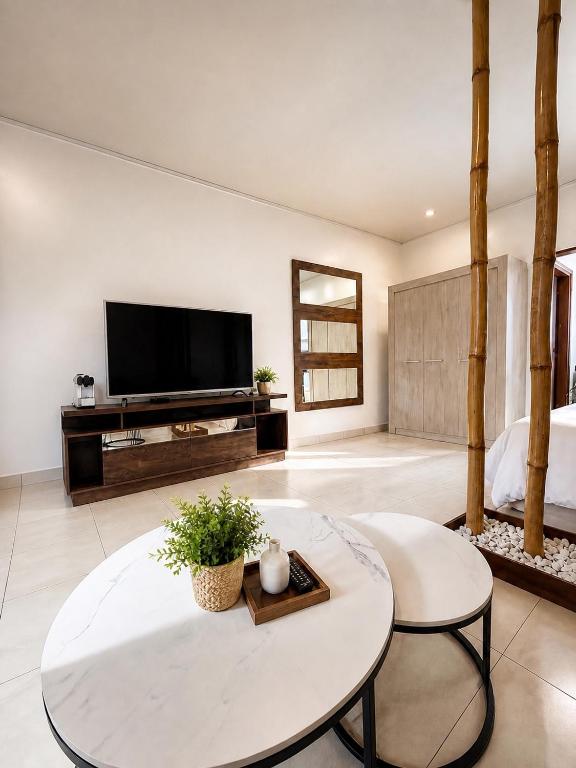 ein Wohnzimmer mit Fernseher und Tisch in der Unterkunft Garden Apartment Abidjan in Abidjan
