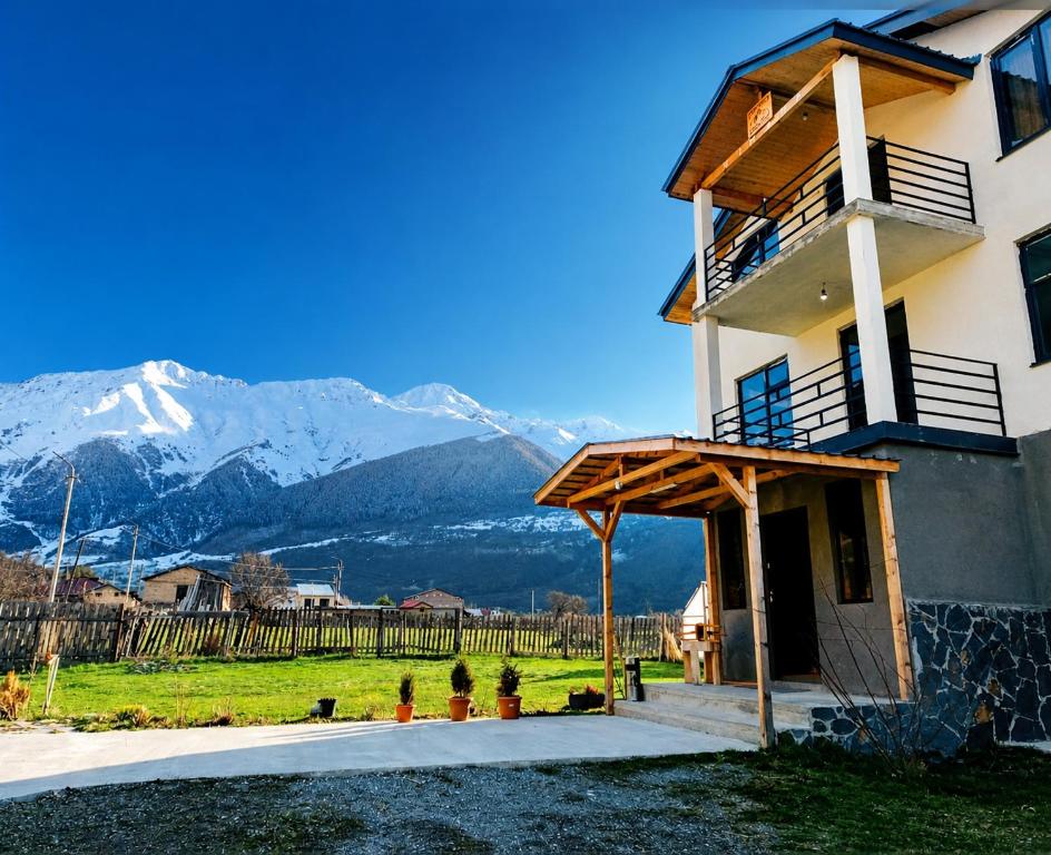 a building with a porch with mountains in the background at Ninama in Mestia