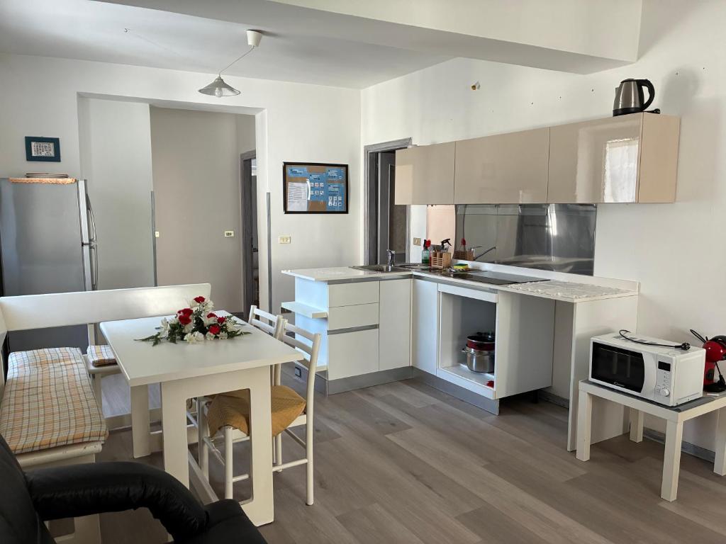 a kitchen with white cabinets and a table with a microwave at Appartamento Michela in Darzo