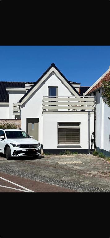a white house with a car parked in front of it at Salty Breeze - Free Parking, quietly situated close to centre and beach! in Noordwijk