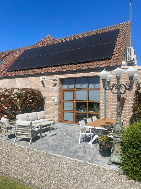 eine Terrasse mit Tisch, Bänken und Solarpaneelen in der Unterkunft Apollonia in Aalter