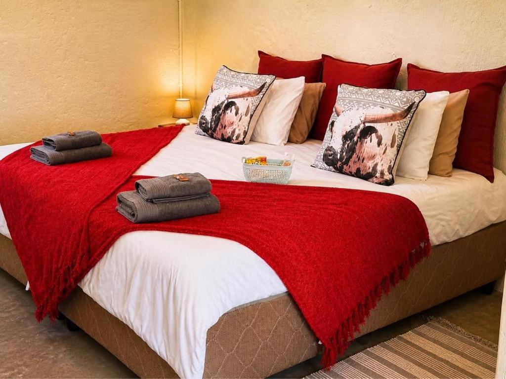 a bedroom with a large bed with red blankets and pillows at Green Elephant Cottages Uis in Uis