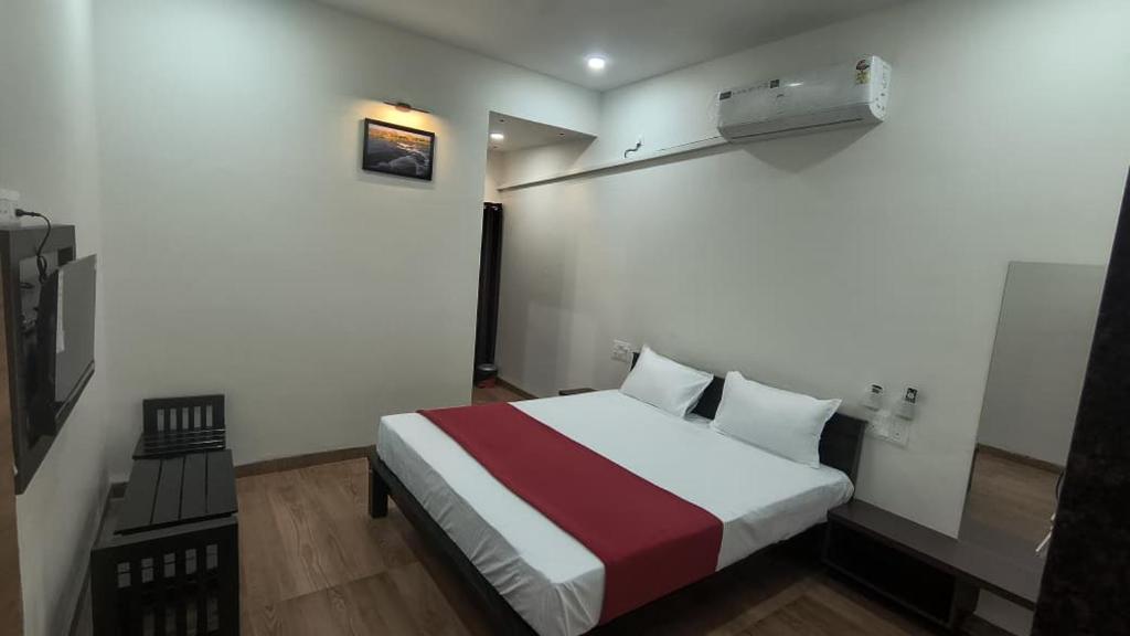 a bedroom with a bed with a red and white blanket at Hills inn lodge in Hospet