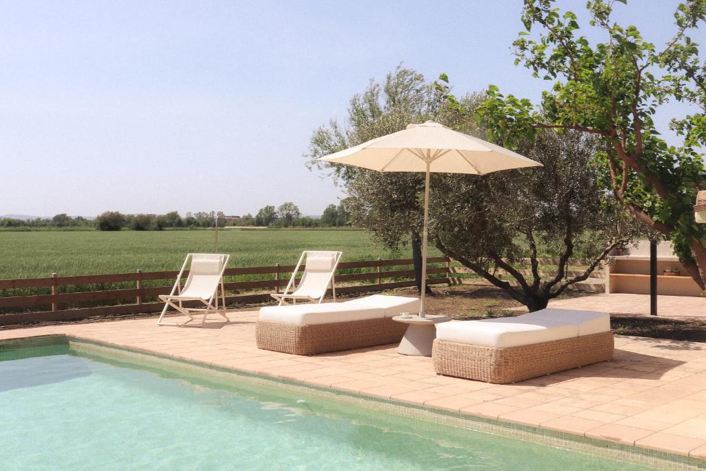 two chairs and an umbrella next to a swimming pool at Mas Les Arrabassades in Castelló d'Empúries