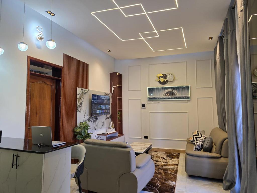 a living room with a desk and chairs and a laptop at Bwera-Comfortable Homes in Kasese