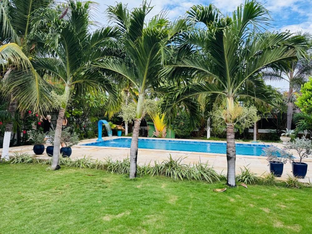 a swimming pool with palm trees in a yard at Casa Flamboyant Parajuru in Beberibe